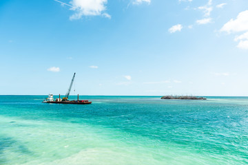 Naklejka na ściany i meble Marathon, USA Florida construction site crane building on island with colorful vibrant turquoise sunny water on gulf of mexico, industrial landscape