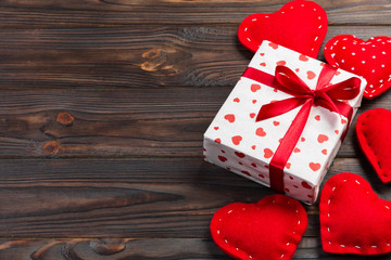 Valentine or other holiday handmade present in paper with red hearts and gifts box in holiday wrapper. Present box of gift on Dark wooden table top view with copy space, empty space for design