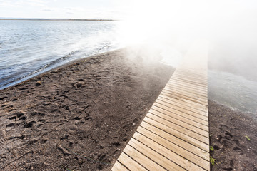Laugarvatn lake in south Iceland on Golden Circle, shore water closeup Hot Springs Geothermal area, sunny day, steam vapor hot mist and wood boardwalk - obrazy, fototapety, plakaty