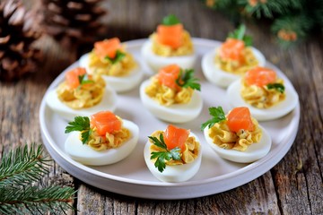 Stuffed chicken eggs with soft cheese, capers and salted salmon. Christmas background.