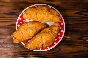 Plate with croissants on a wooden table. Top view