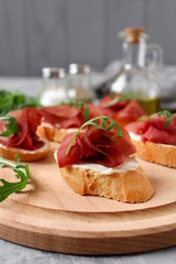 Canape or crostini with toasted baguette, light cheese, bresaola and arugula on wooden board. Diet food. Iron food.