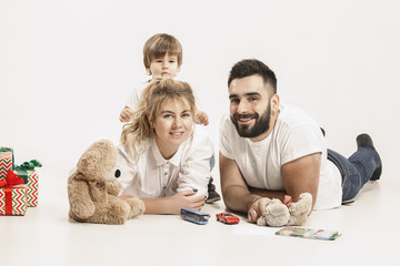 The happy family with kid posing together on white studio background