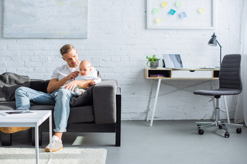 father sitting on couch and holding baby daughter in living room