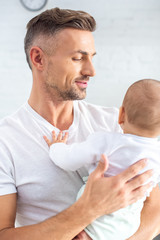 Fototapeta premium handsome father holding baby at home