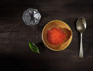red caviar and a glass of vodka on a wooden background. top view. rustic style.