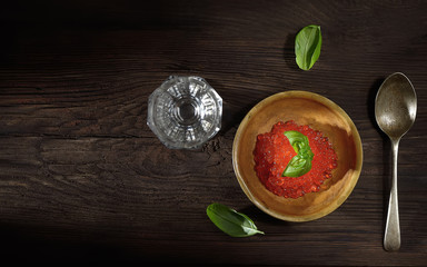 red caviar and a glass of vodka on a wooden background. top view. rustic style.