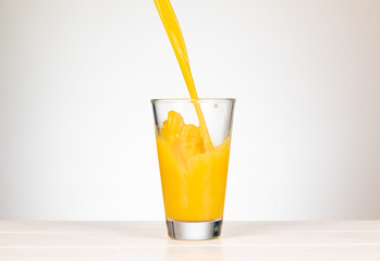 pour orange juice in a glass with splashing