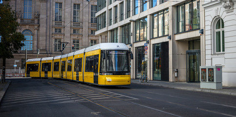 Public transportation concept. Yellow electric tram travels at Berlin's town, Germany. Buildings background, banner. - obrazy, fototapety, plakaty