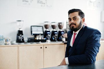 Fototapeta na wymiar Stylish beard indian business man on suit sitting at cafe.