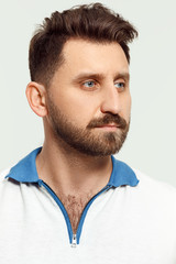 Fototapeta premium Serious man standing, looking at camera isolated on white studio background. Beautiful, young face. male half-length portrait. Human emotions, facial expression concept.