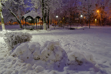 snow-covered gazebo in the city Park on a winter night