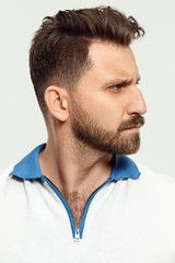 Fototapeta premium Serious man standing, looking at camera isolated on white studio background. Beautiful, young face. male half-length portrait. Human emotions, facial expression concept.