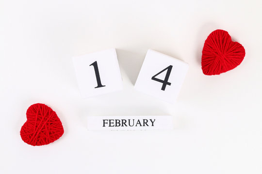 Red homemade diy heart made cardboard, yarn, wooden perpetual calendar on white background. Idea St. Valentines Day, day love, February 14 concept. Copy space, top view, flat lay composition.