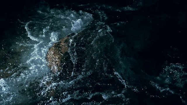 Slow motion of waves on dark water surface with play of flecks of bright light close up. Amazing dramatic natural background. Shooting with 180fps. Epic mystical and magic night view. Crystal clear