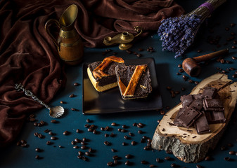 Arrangement of slice chocolate cake and pieces of coffee and chocolate on dark background. Homemade chocolate cake served with pieces of chocolate. Holiday arrangement