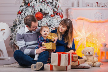 Merry Christmas celebration. Happy family mother father and baby at christmas tree with Xmas gifts at home.