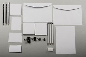 A mock up of a template table with a blank envelope, notepad and a cup of coffee with stationery in a gray background. View from above. Flat lay. Layout for the designer.