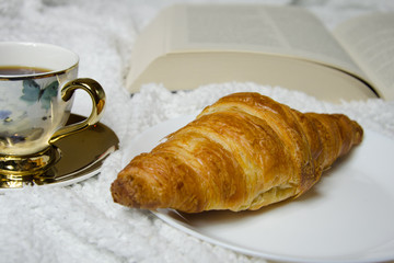 croissant, cup of coffee and book