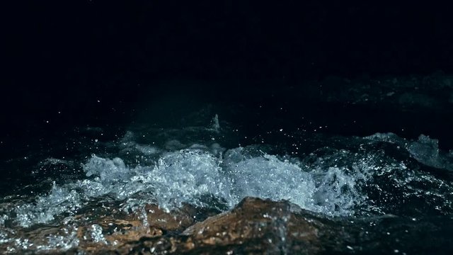 Slow motion of waves on dark water surface with play of flecks of bright light close up. Amazing dramatic natural background. Shooting with 180fps. Epic mystical and magic night view. Crystal clear