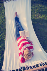 woman reading a book while relaxing on hammock