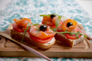 Healthy snack or salmon fish, arugula, olives and creamy cheese on toast bread. French or italian organic breakfast