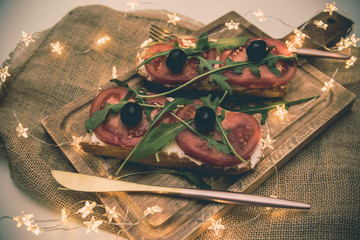 Healthy snack or Tomato, arugula, olives and creamy cheese on toast bread. French or italian Organic breakfast 