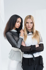 attractive multiethnic women in black and white clothes standing and looking at camera together isolated on white