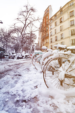 Bicycles in snow at parking lot along the street