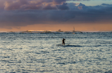silhouette of paddle boarder at sunset