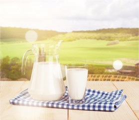 Glass of milk and jug on blurred background