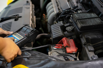 mechanic use voltmeter checking voltage of car battery in car service centre
