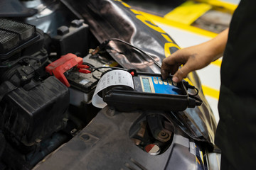 Fototapeta na wymiar mechanic use voltmeter checking voltage of car battery in car service centre