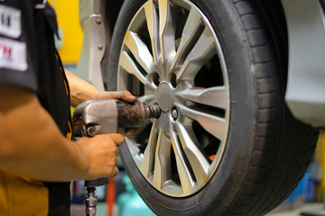 Fototapeta premium Mechanician changing car wheel in auto repair shop