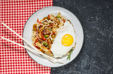 Udon stir-fry noodles with chicken on black stone background