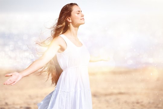 Happy woman with arms open on natural background