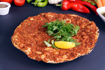 Traditional delicious Turkish foods; Lahmacun (Turkish pizza). Lahmacun traditional Turkish pizza and with salad isolated on dark table.