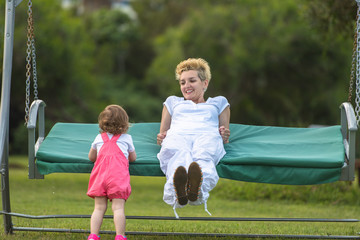 Obraz premium mother and little daughter swinging at backyard