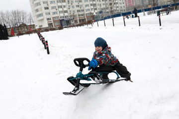 Fototapeta na wymiar Child slides on snow scooter