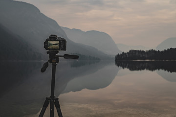 camera on tripod at work on a misty lakeshore