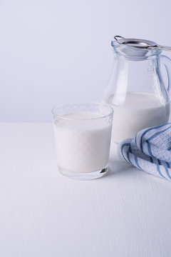 fresh milk in glass jug and glass on white background