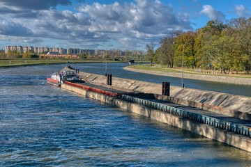 Fototapeta na wymiar an empty barge for transporting coal flows into locks, in the background an autumn sunny landscape