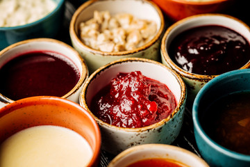 Set of different sauces on black wooden background.