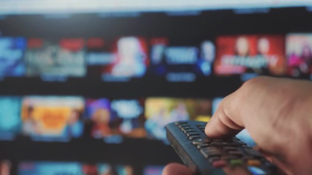 online video streaming service. with apps and hand. smart tv. Male hand holding remote the control turn off smart tv. man hand controls holding remote. concept internet online cinema lifestyle