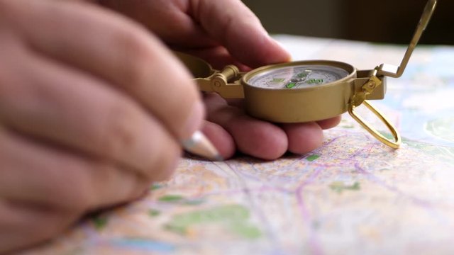 Man searching direction with a compass on background of map. Finding your way concept