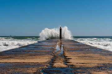 After the storm scene with a wet pier ending in the unleashed waters of a stormy sea in Cascais, Portugal.