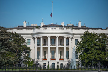 Fototapeta na wymiar The White House, Home of the President of the United States of America in Washington, DC USA on Blue sky background. Half Staff Flag Status.