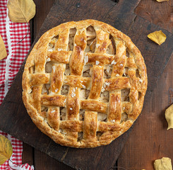 baked whole round apple pie on a brown wooden board