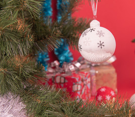Белый елочный шар со снежинками висит на елке с подарками