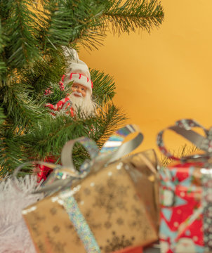 Дед Мороз смотрит из-за елки на подарки